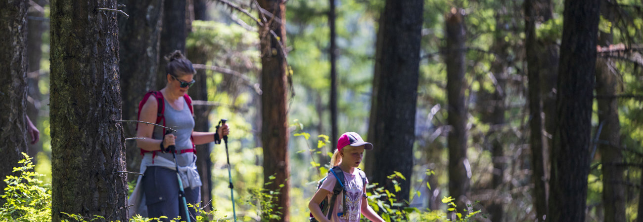 Mother and daughter on a hike at Holland Lake with trees in the background