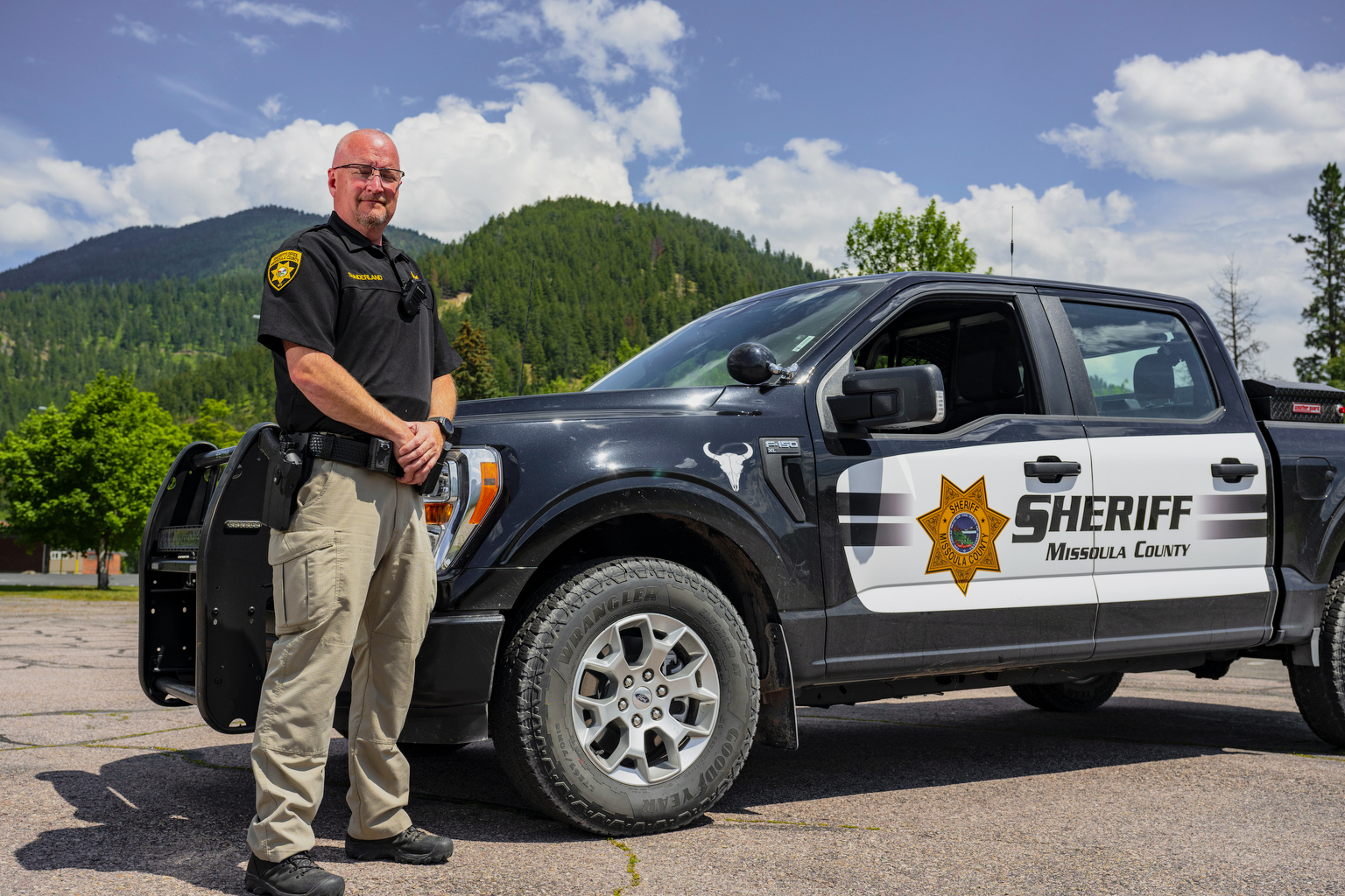 Sheriff's Office deputy standing with truck with mountains in the background